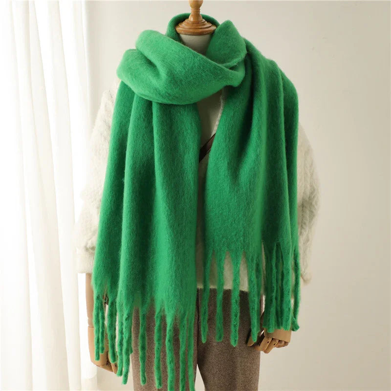 Soft green wool scarf with fringed edges draped on mannequin wearing white sweater and brown pants
