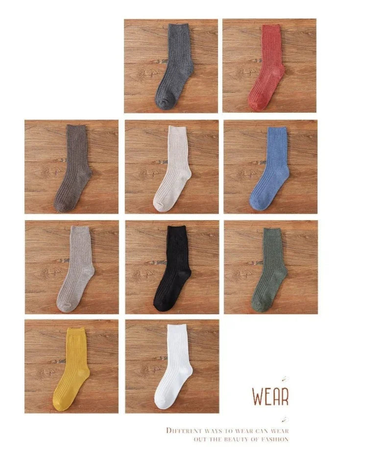 collection of ribbed knit socks in various colors on wooden background, including gray, red, brown, beige, blue, black, green, yellow, and white