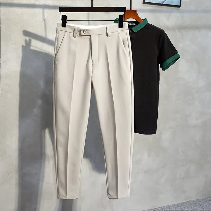 Beige slim-fit trousers and black short-sleeve polo shirt with green collar displayed on hangers