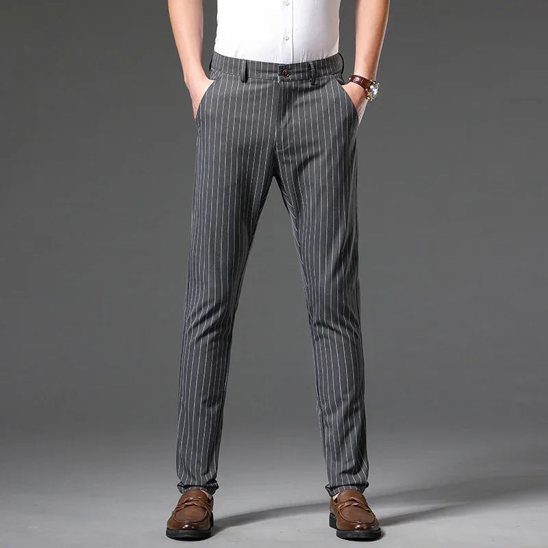 Man wearing gray pinstripe dress pants with brown loafers on gray background