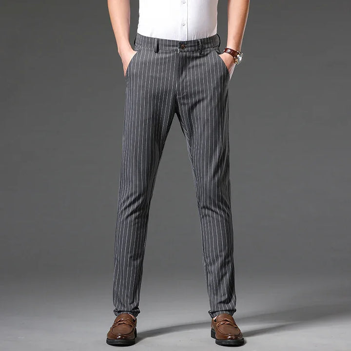 Man wearing gray pinstripe dress pants with brown loafers on gray background