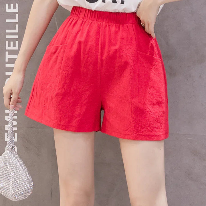 Woman wearing bright red high-waisted casual shorts with elastic waistband and pockets