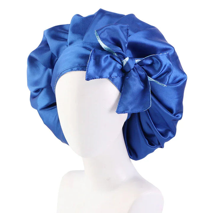 Blue satin bonnet with a large decorative bow displayed on a white mannequin head