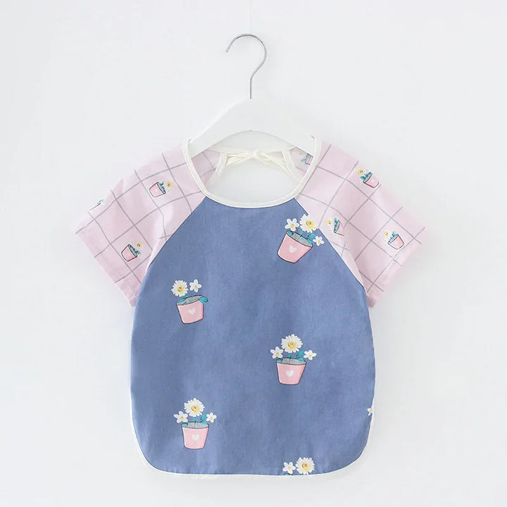 Baby bib with pink checkered sleeves and floral pot print on blue front, hanging on white hanger