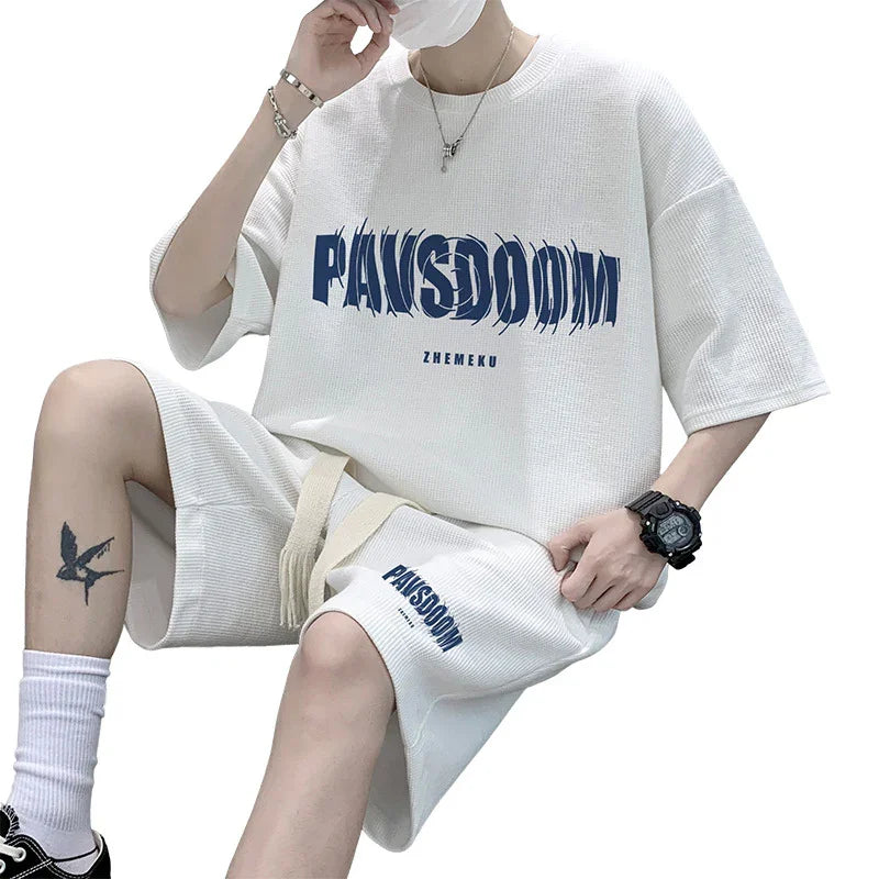 Person wearing white PAN(S)DOOM matching oversized t-shirt and shorts set with accessories and tattoo
