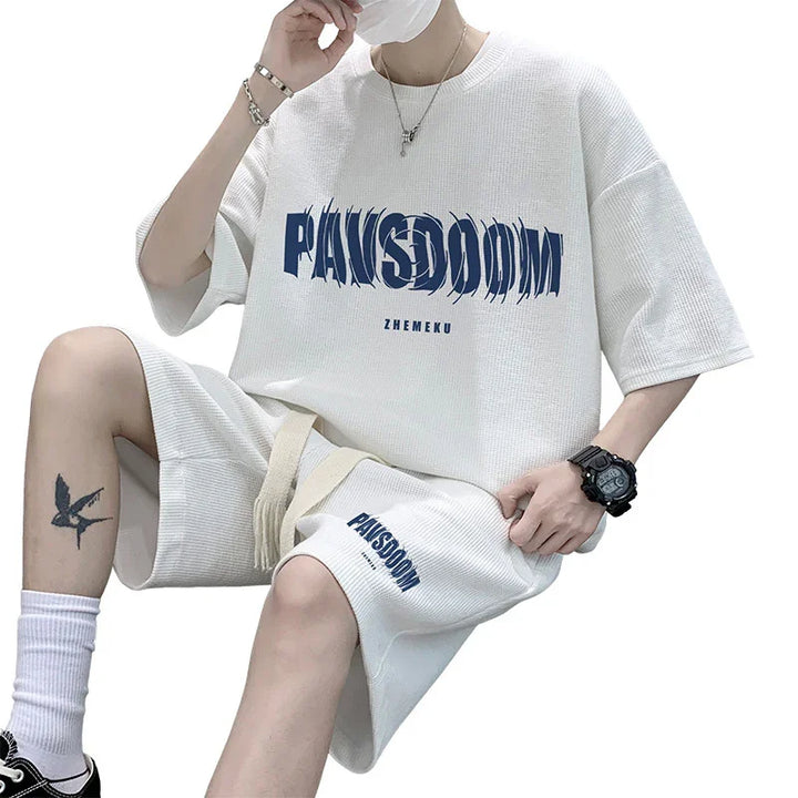 Person wearing white PAN(S)DOOM matching oversized t-shirt and shorts set with accessories and tattoo