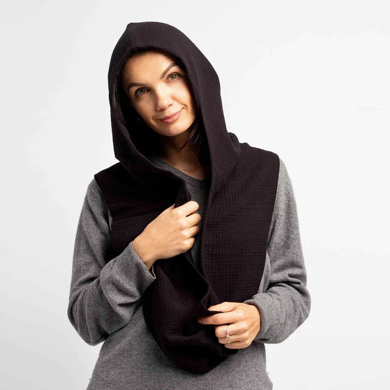 Woman wearing a black textured hooded scarf over a grey long-sleeve top on white background