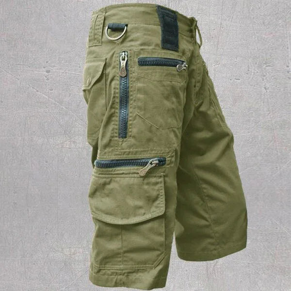olive green cargo shorts with multiple zippered pockets and a D-ring on a gray background