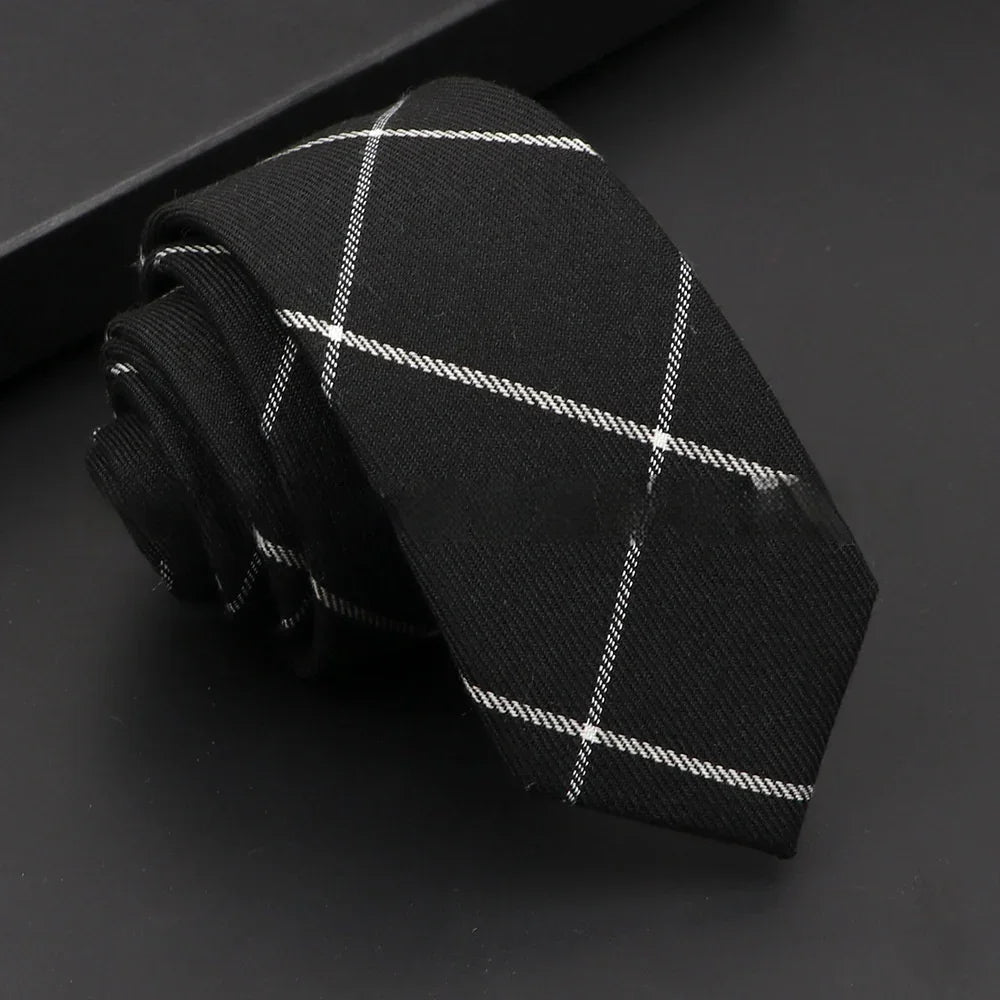 Black necktie with white plaid pattern folded on black surface