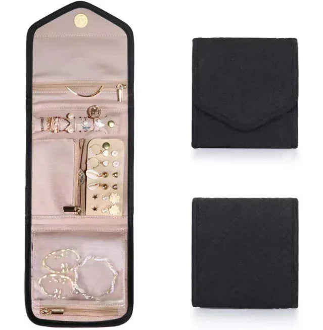 Black foldable jewelry organizer displaying rings, earrings, bracelets in compartments with zipper pockets