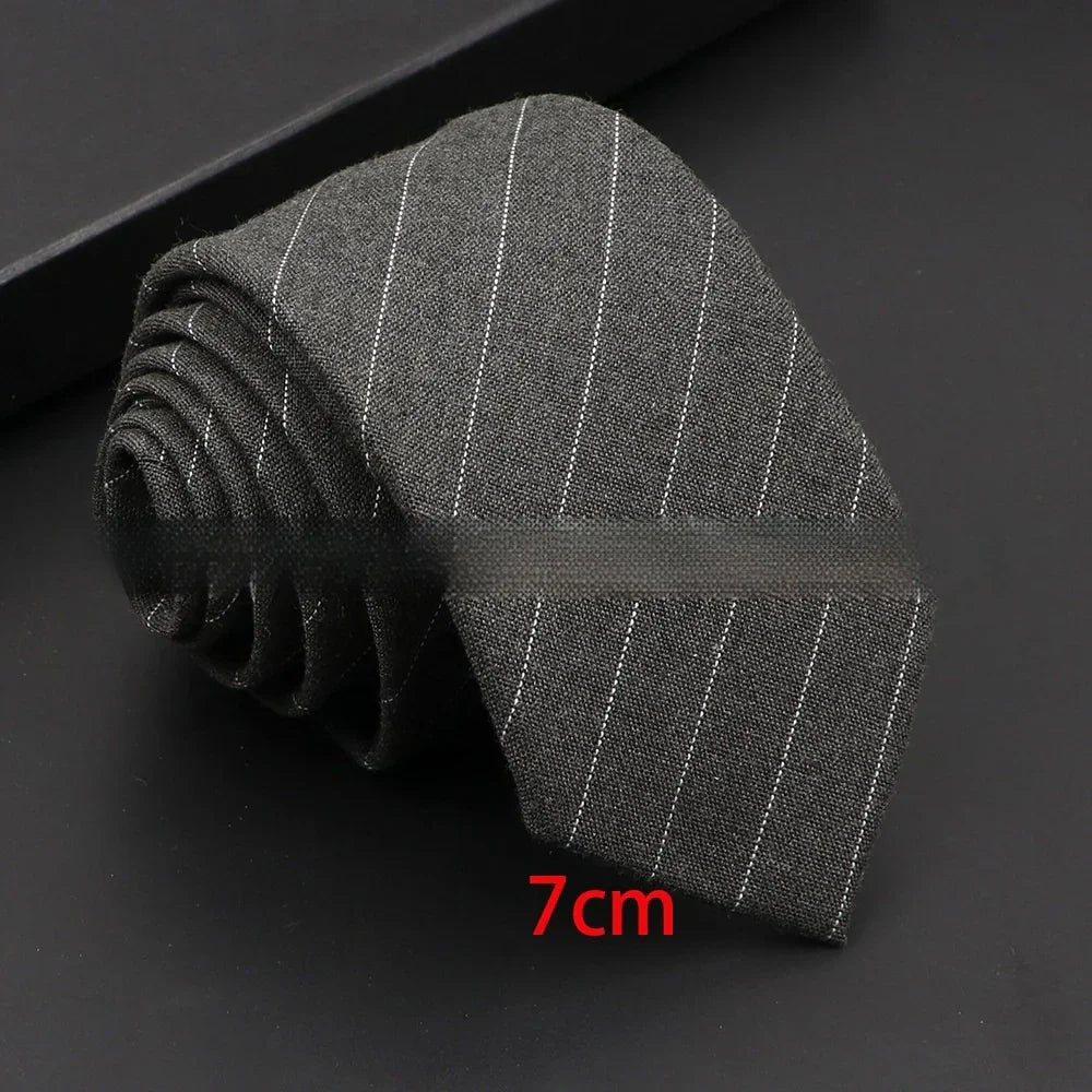 Gray pinstripe necktie rolled on black surface with 7cm width label