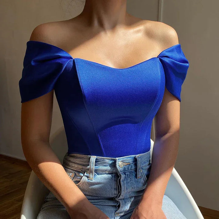 Woman wearing a fitted off-shoulder royal blue top paired with high-waisted light blue jeans