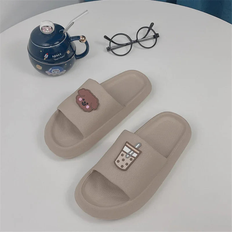 Beige slide sandals with cute puppy and bubble tea decorations on a white round table with black glasses and blue teapot