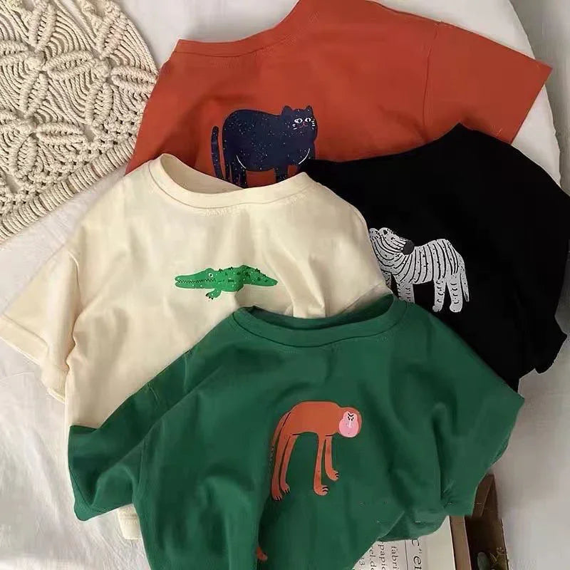 Four colorful t-shirts with animal prints: black cat on orange, white crocodile on beige, white zebra on black, and pink-faced monkey on green