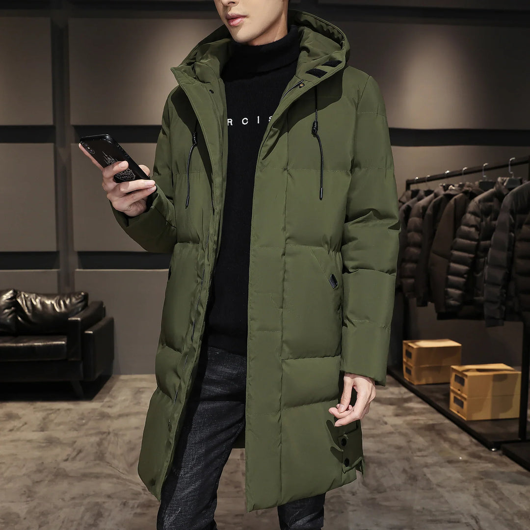Man wearing green hooded winter puffer jacket in a modern store with black coats on rack