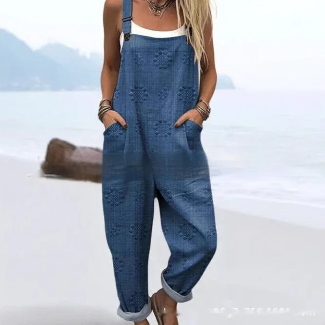 Woman wearing blue textured floral overalls with rolled cuffs on a beach background