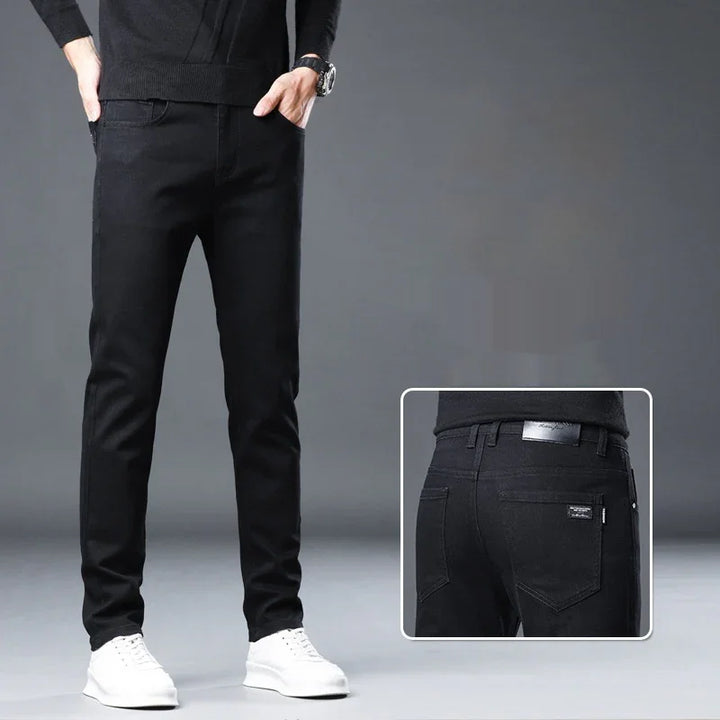 Man wearing slim fit black jeans and white sneakers on grey background with back pocket detail