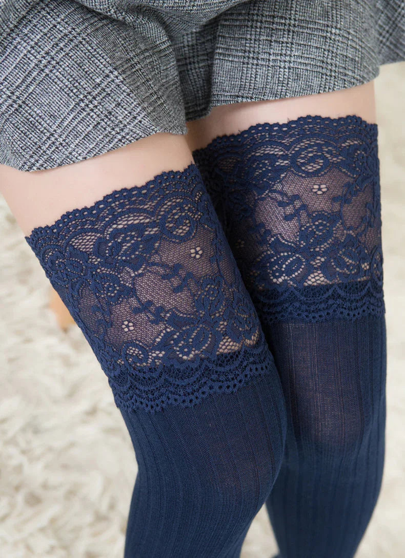 Close-up of legs wearing navy blue lace-top thigh-high socks paired with a gray plaid skirt