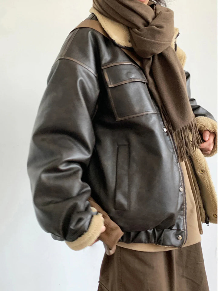 Person wearing dark brown leather shearling jacket and brown wool scarf against white background