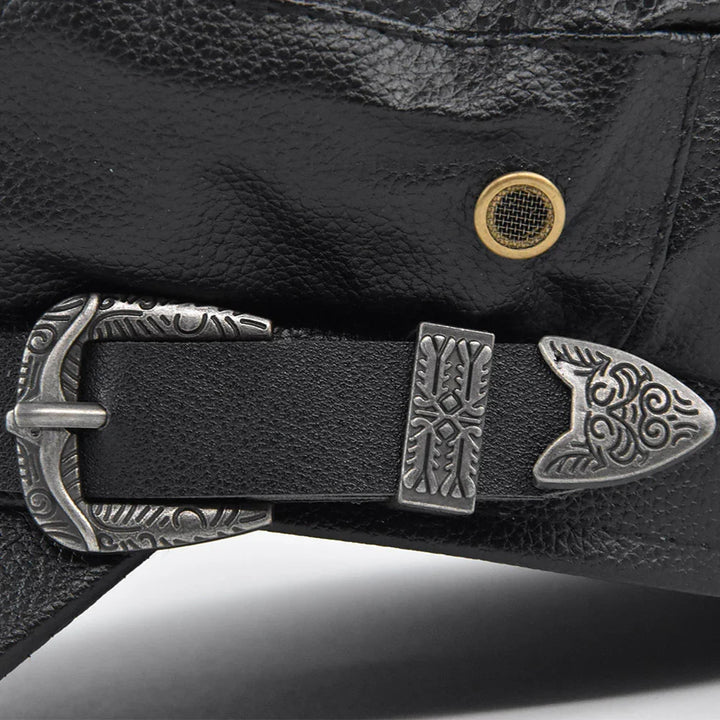 Close-up of black leather bag with detailed engraved silver buckle and brass grommet