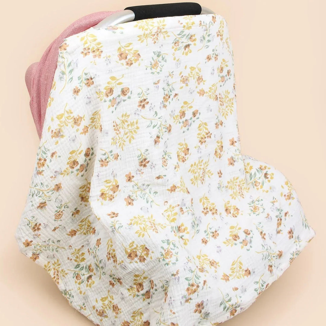 Floral-patterned white muslin baby car seat cover with muted yellow and brown flowers