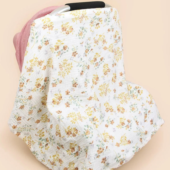 Floral-patterned white muslin baby car seat cover with muted yellow and brown flowers