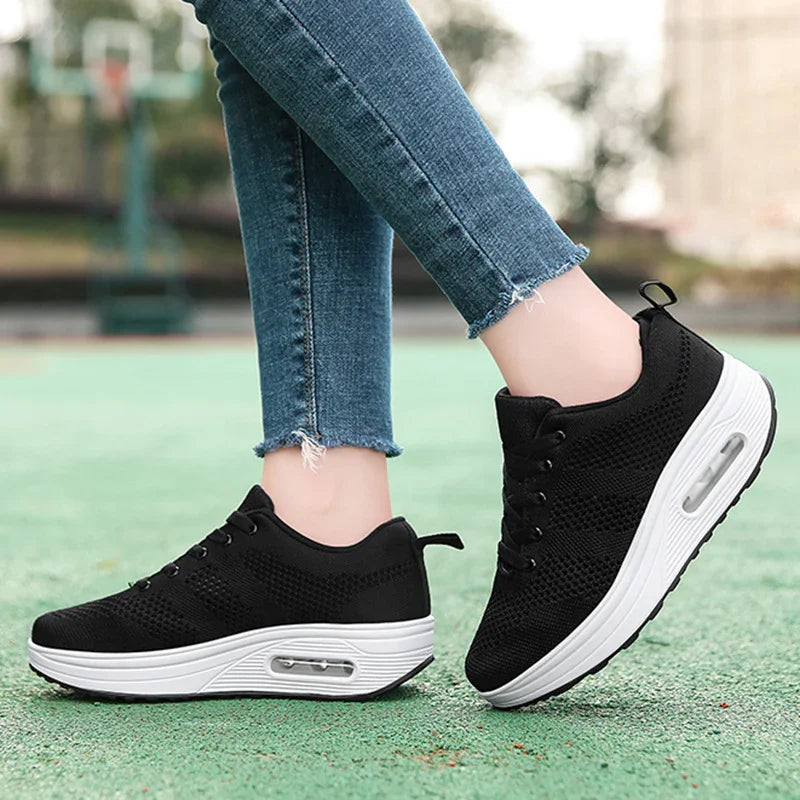 Black mesh sneakers with white air cushion soles worn with frayed hem blue skinny jeans on green outdoor court