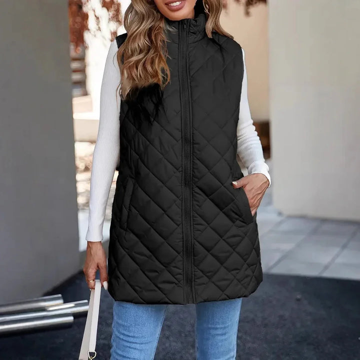 Woman wearing black quilted sleeveless vest with zipper over white long sleeve top and blue jeans