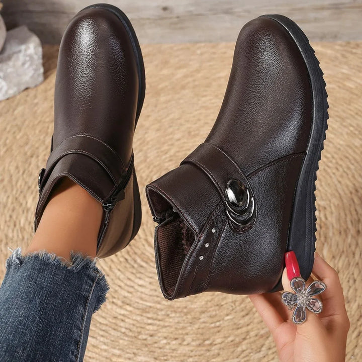 Dark brown leather ankle boots with side zipper and decorative button on woven mat background