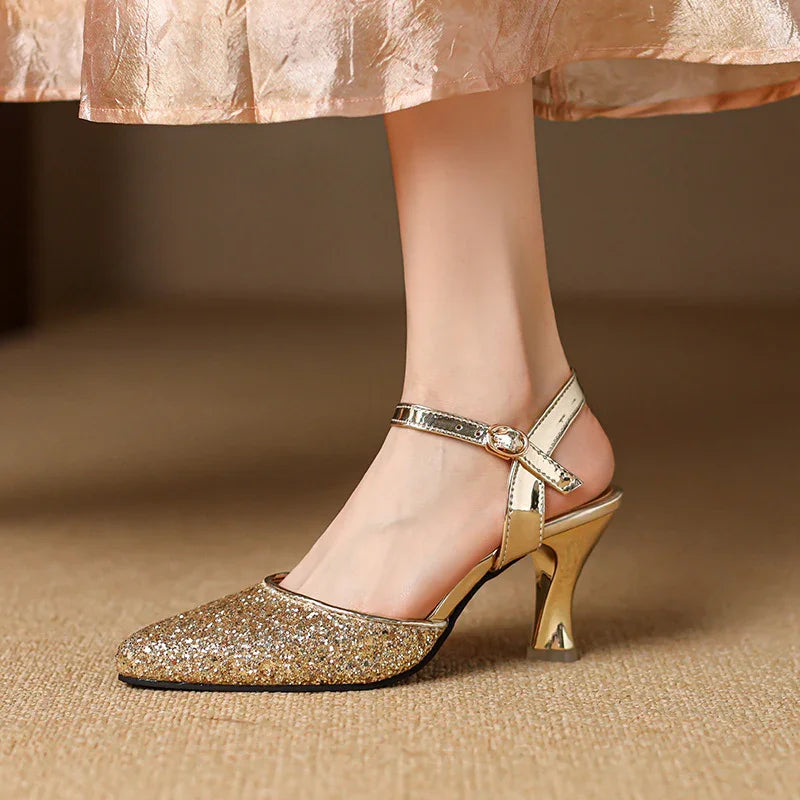Women's gold glitter pointed toe high heel shoe with ankle strap on carpet
