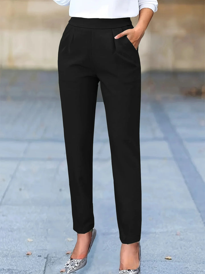 Woman wearing black tapered pants with pockets and silver high heels on pavement