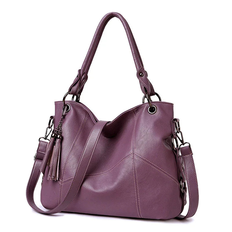 Stylish purple leather handbag with double handles, detachable shoulder strap, and tassel detail
