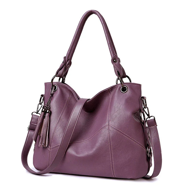 Stylish purple leather handbag with double handles, detachable shoulder strap, and tassel detail