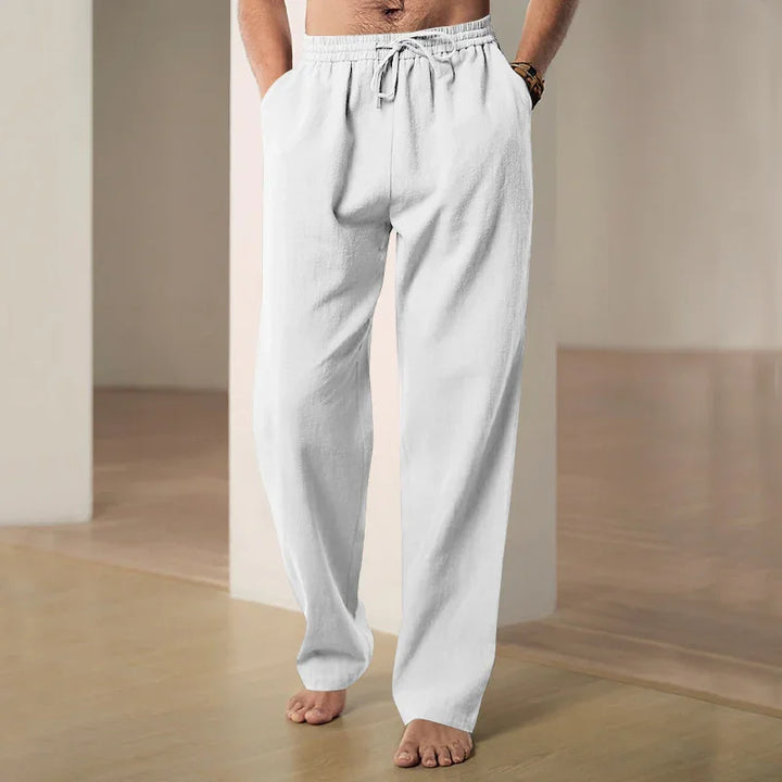 man wearing white drawstring lounge pants barefoot in minimal indoor setting