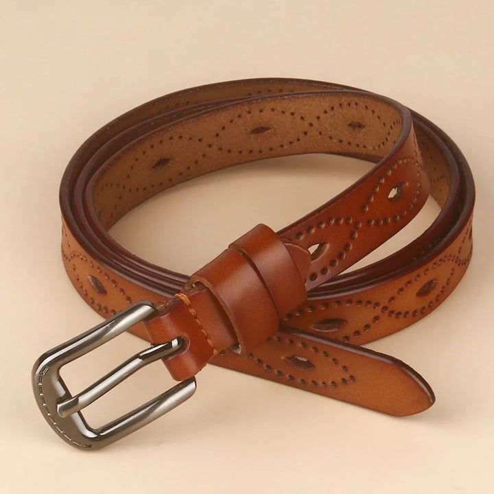 Brown leather belt with metal buckle and decorative perforated pattern rolled on beige background