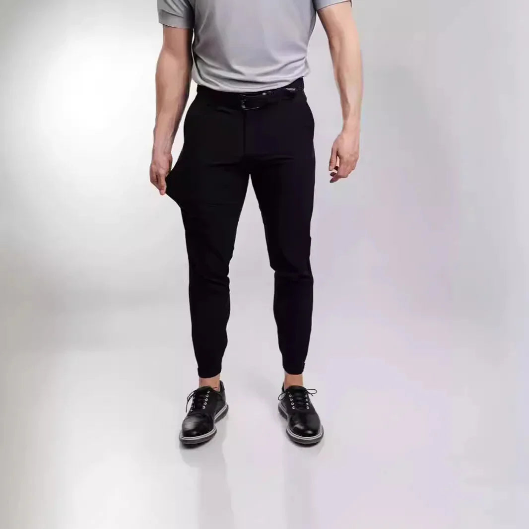 Man wearing black tailored jogger pants and black leather shoes against plain background