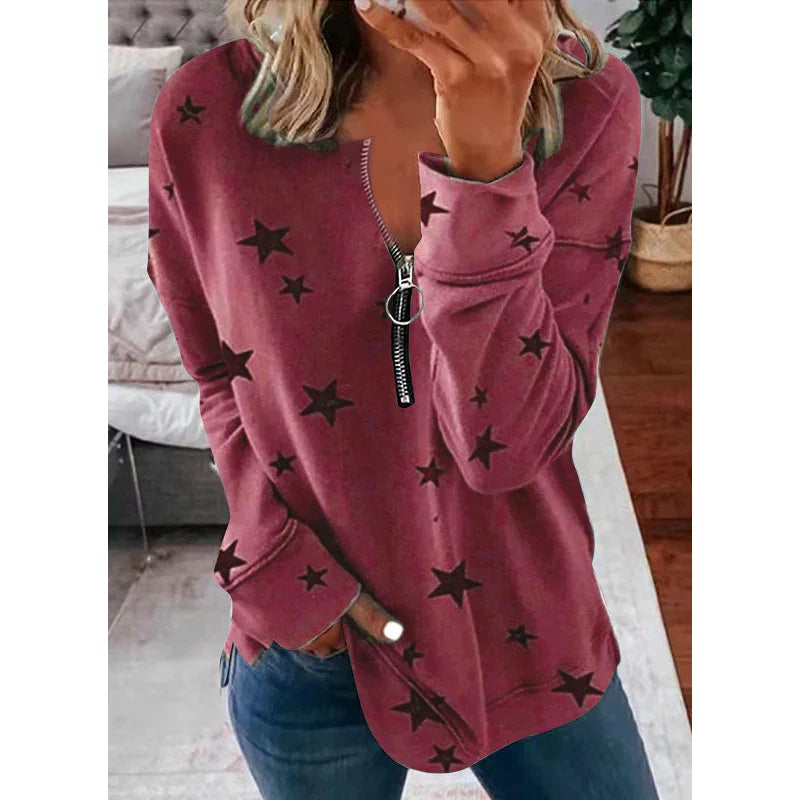 Woman wearing a mauve star-print long sleeve top with front zipper in a cozy living room