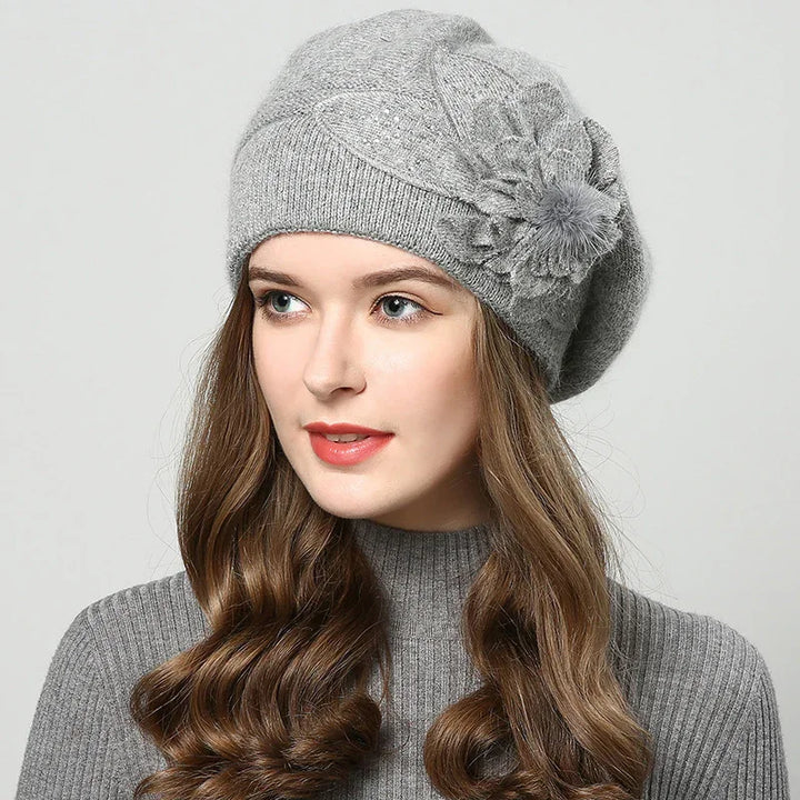 Woman wearing a grey knit beret with flower detail and matching ribbed sweater