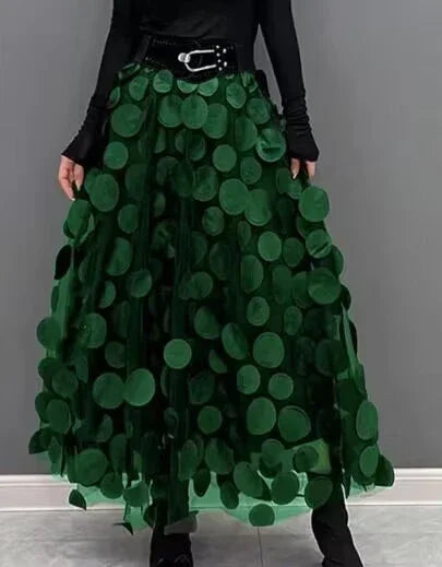 Elegant green maxi skirt with large circular appliques, paired with black long-sleeve top and waist belt
