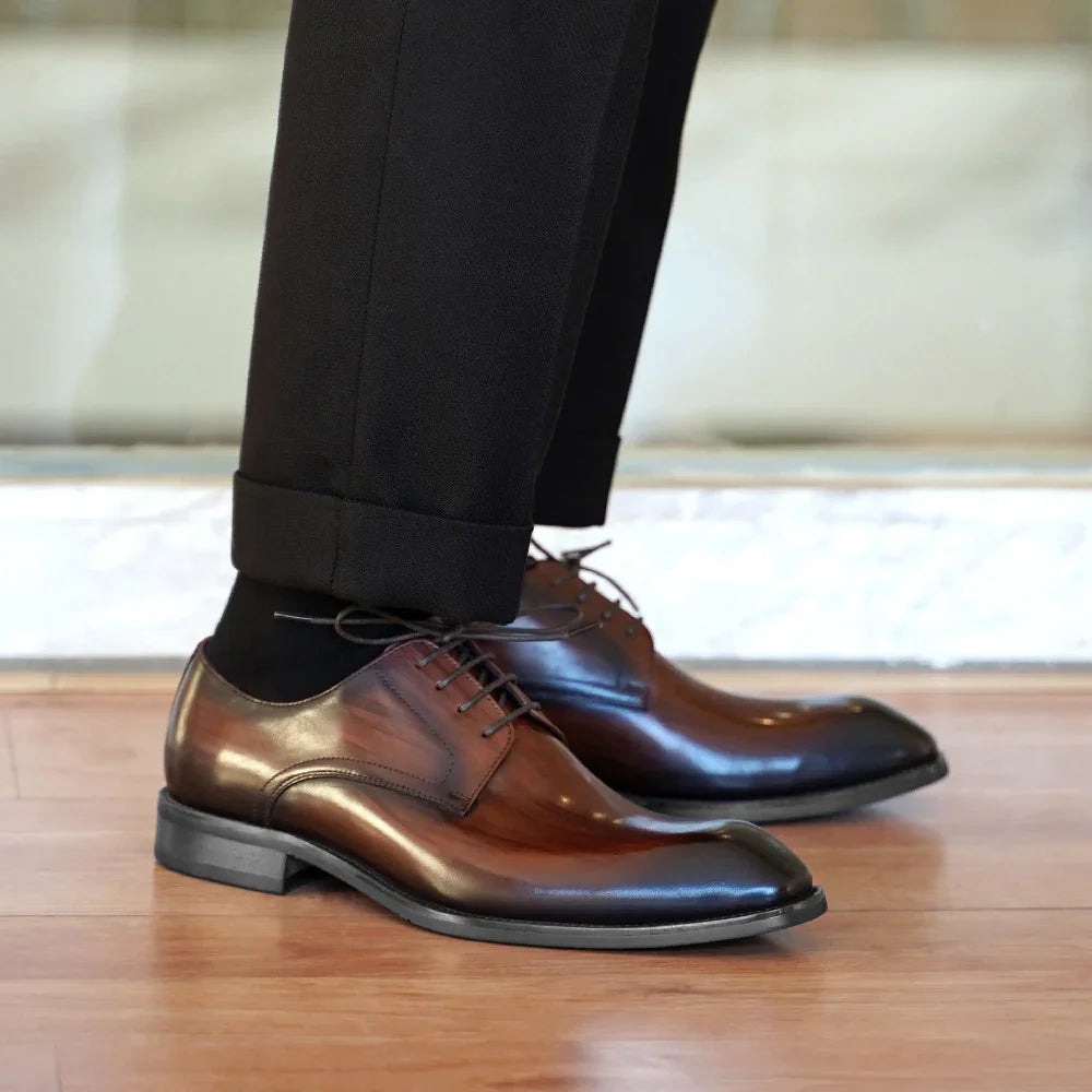 Close-up of polished brown leather dress shoes worn with black trousers on wooden floor