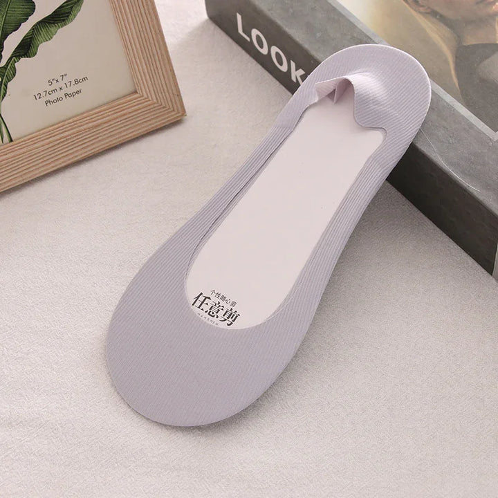 Gray no-show liner sock with ribbed texture on beige surface next to photo frame and book