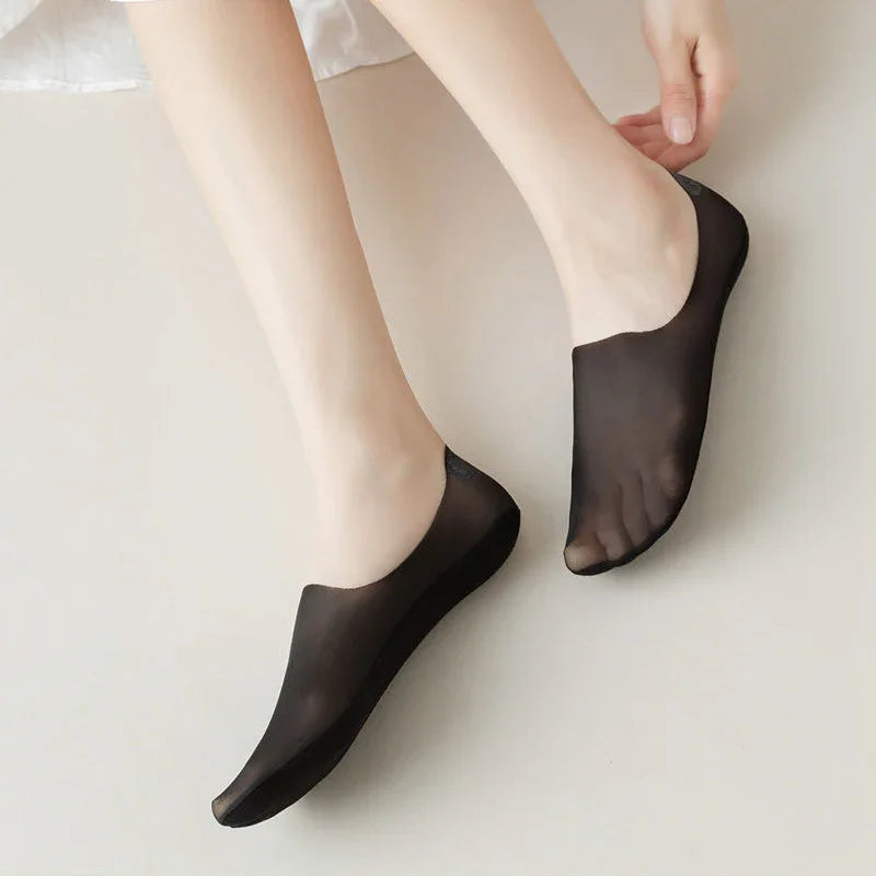 Feet wearing sheer black no-show socks on a light floor surface