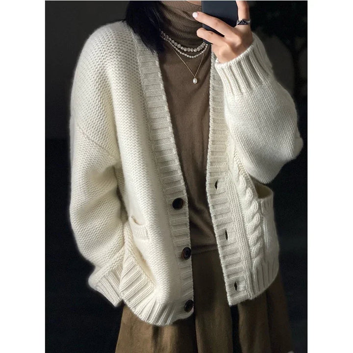 Woman wearing a cream knit cardigan with large buttons over a brown turtleneck and layered pearl necklaces