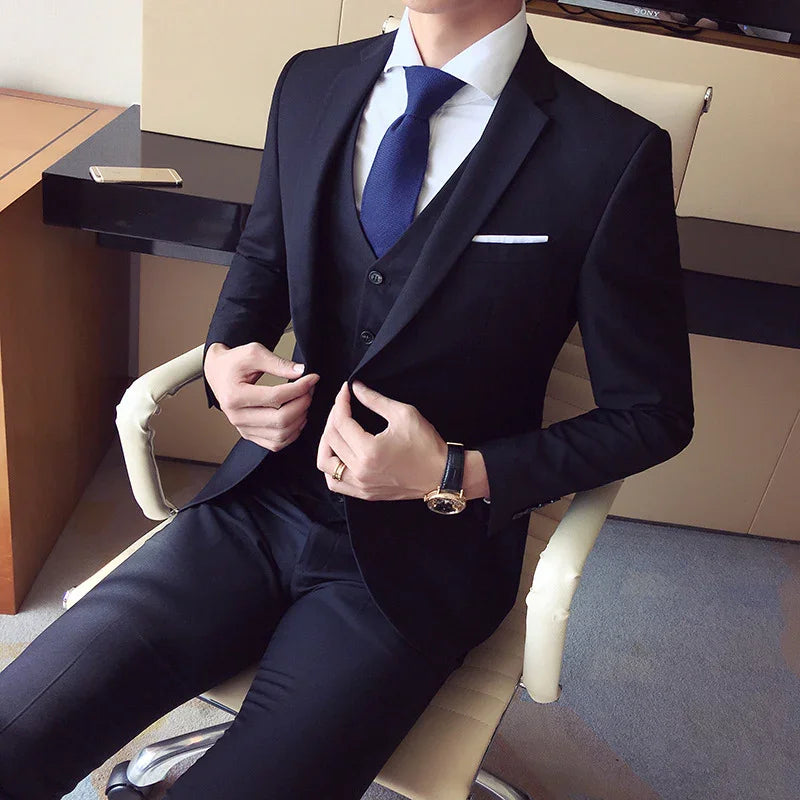 Man wearing black suit with white shirt and blue tie sitting in office chair adjusting jacket