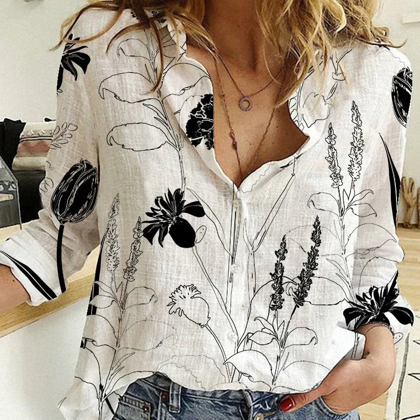 Woman wearing white button-up blouse with black floral print, paired with blue jeans, indoors
