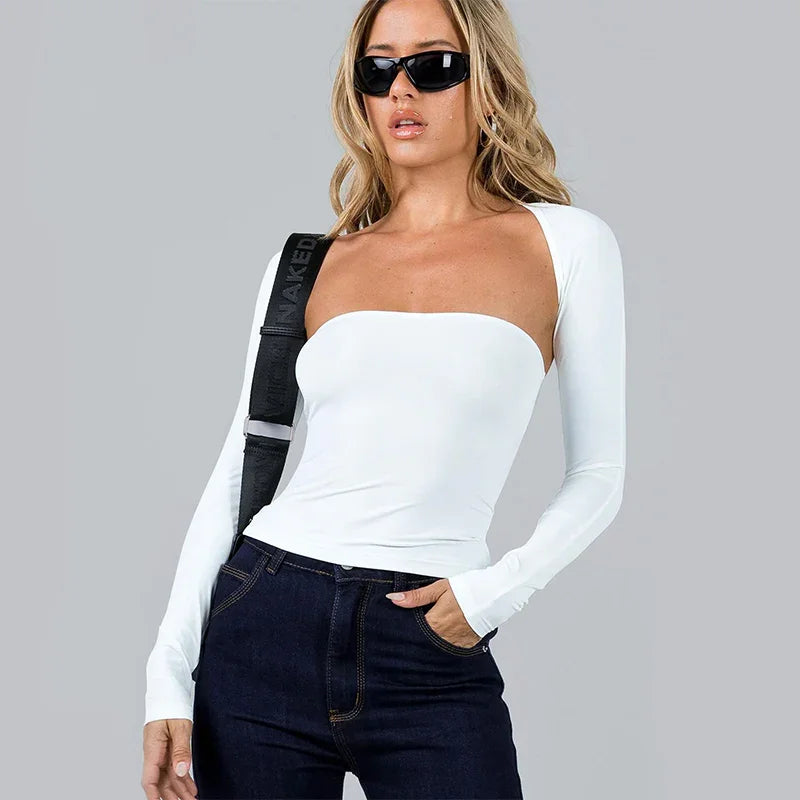 Woman wearing white one-shoulder long sleeve top and dark jeans with black sunglasses and shoulder strap