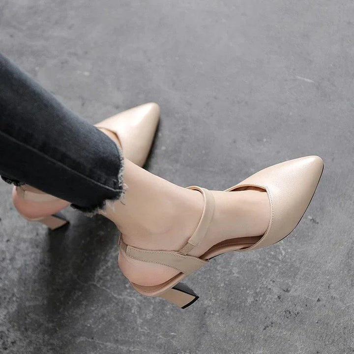 Beige pointed-toe high heel slingback shoes worn with frayed hem black jeans on gray floor