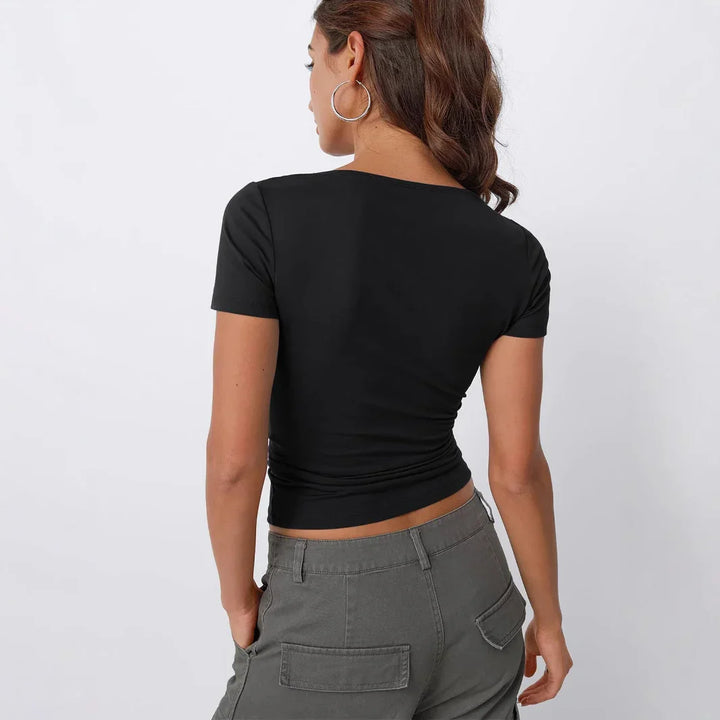 Woman wearing black short-sleeve fitted crop top and gray cargo pants, back view