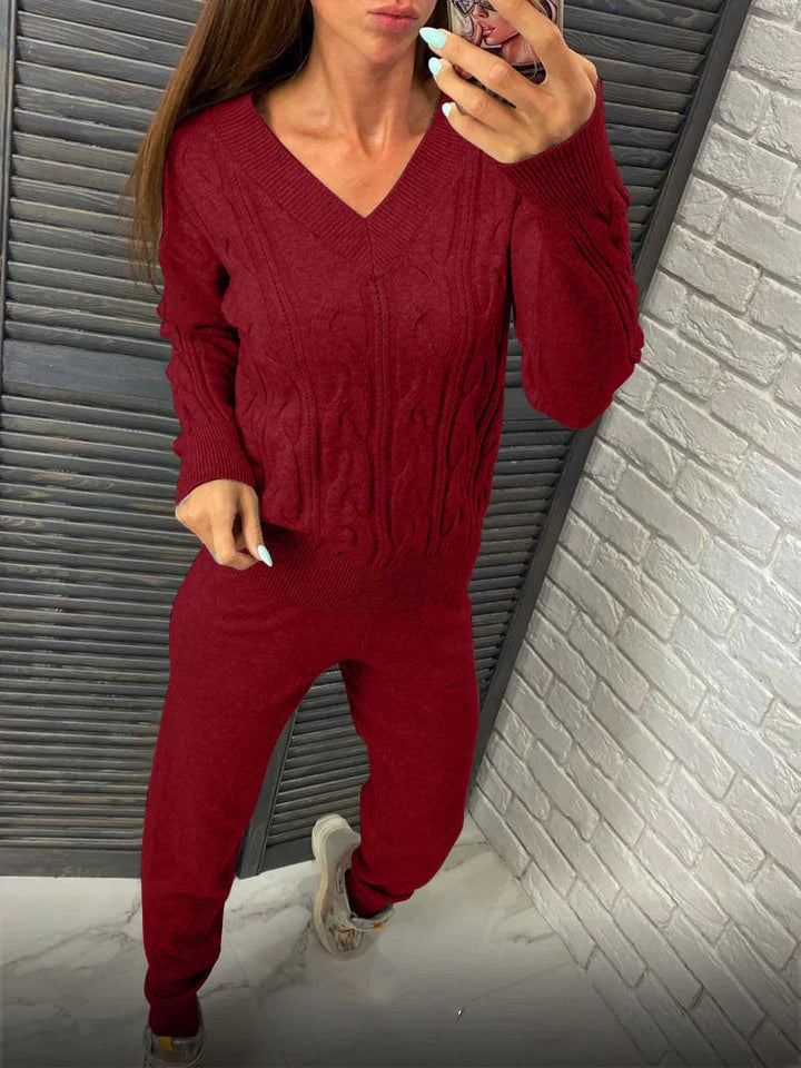 Woman wearing a burgundy cable knit sweater and matching pants taking a mirror selfie indoors