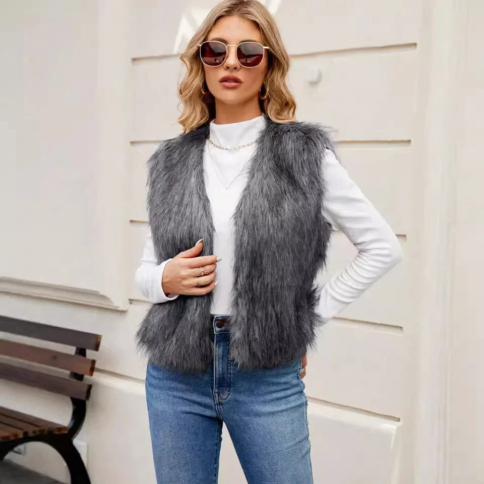 Woman wearing grey faux fur vest over white long-sleeve top and blue jeans with sunglasses